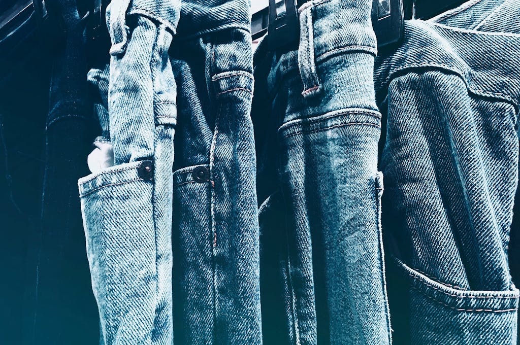 A collection of blue denim jeans hanging closely on a rack in a retail store.