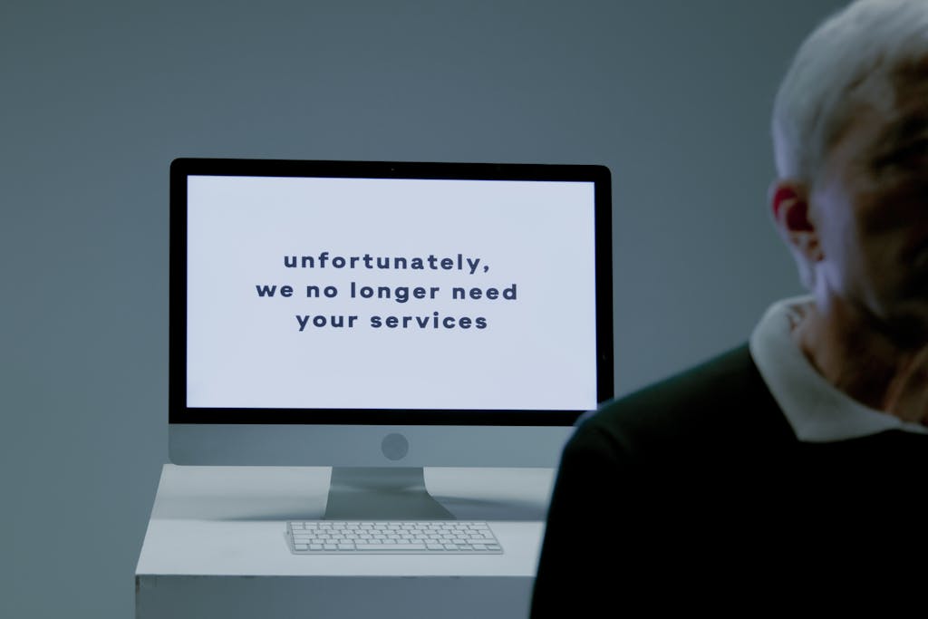 A computer screen displays a termination message, indicating job loss or unemployment.