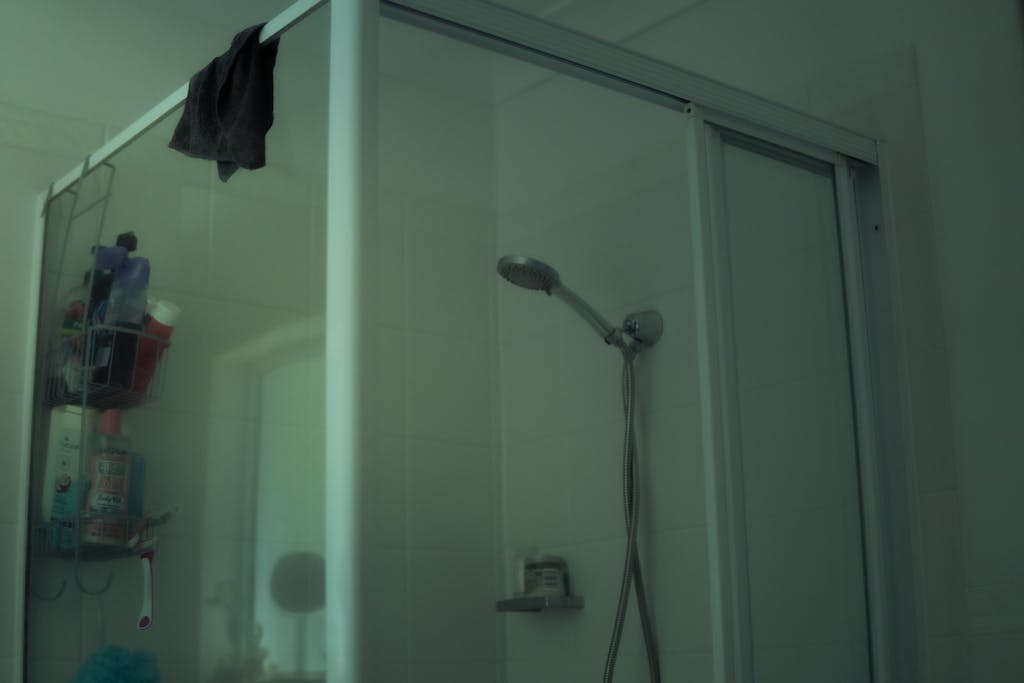 Avoid These 8 Heat Wave Mistakes Before They Harm Your Health 2 A contemporary bathroom shower with a glass door and wall-mounted showerhead.