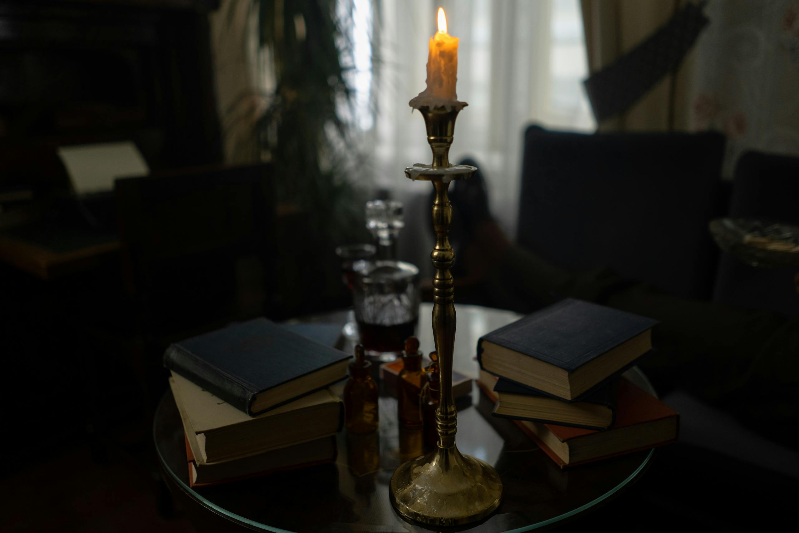 A cozy indoor scene with stacked books and a candle, creating a warm and inviting atmosphere.