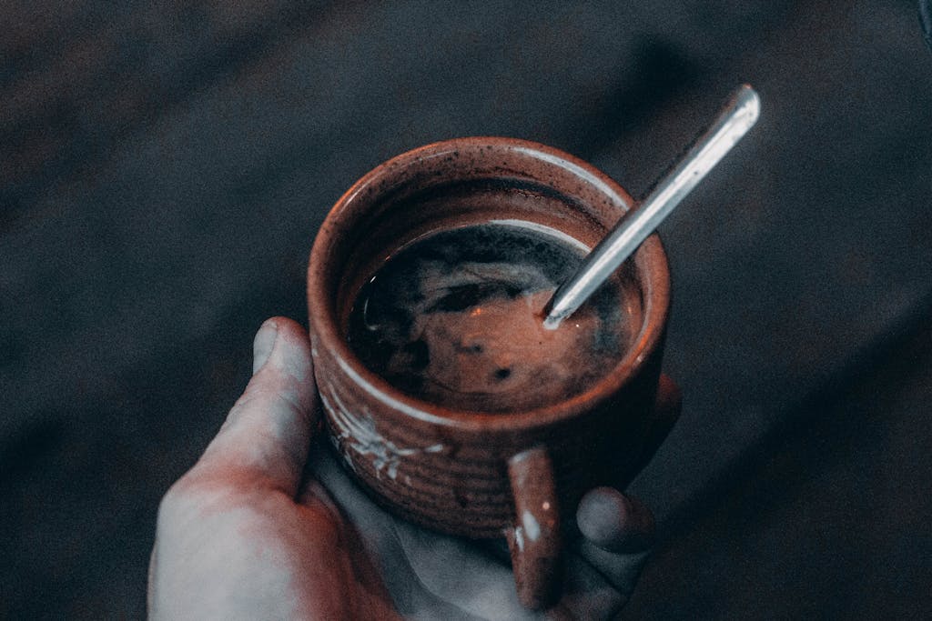 A cozy rustic coffee in a clay cup held by hand, perfect for a chilly day.