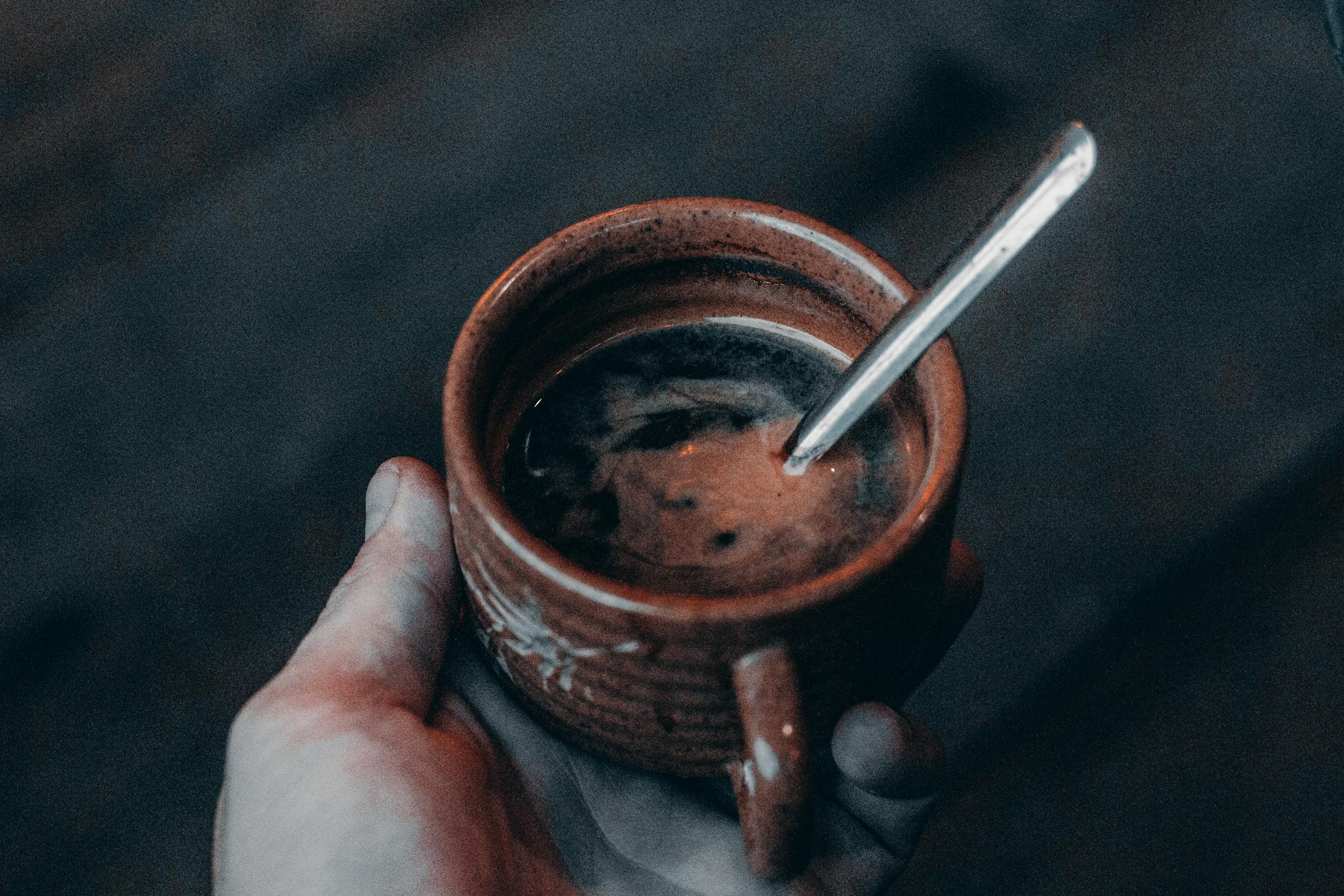 A cozy rustic coffee in a clay cup held by hand, perfect for a chilly day.