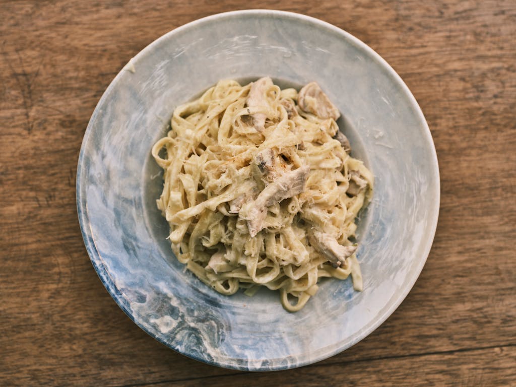 A delicious homemade fettuccine Alfredo pasta dish served on a rustic wooden table.