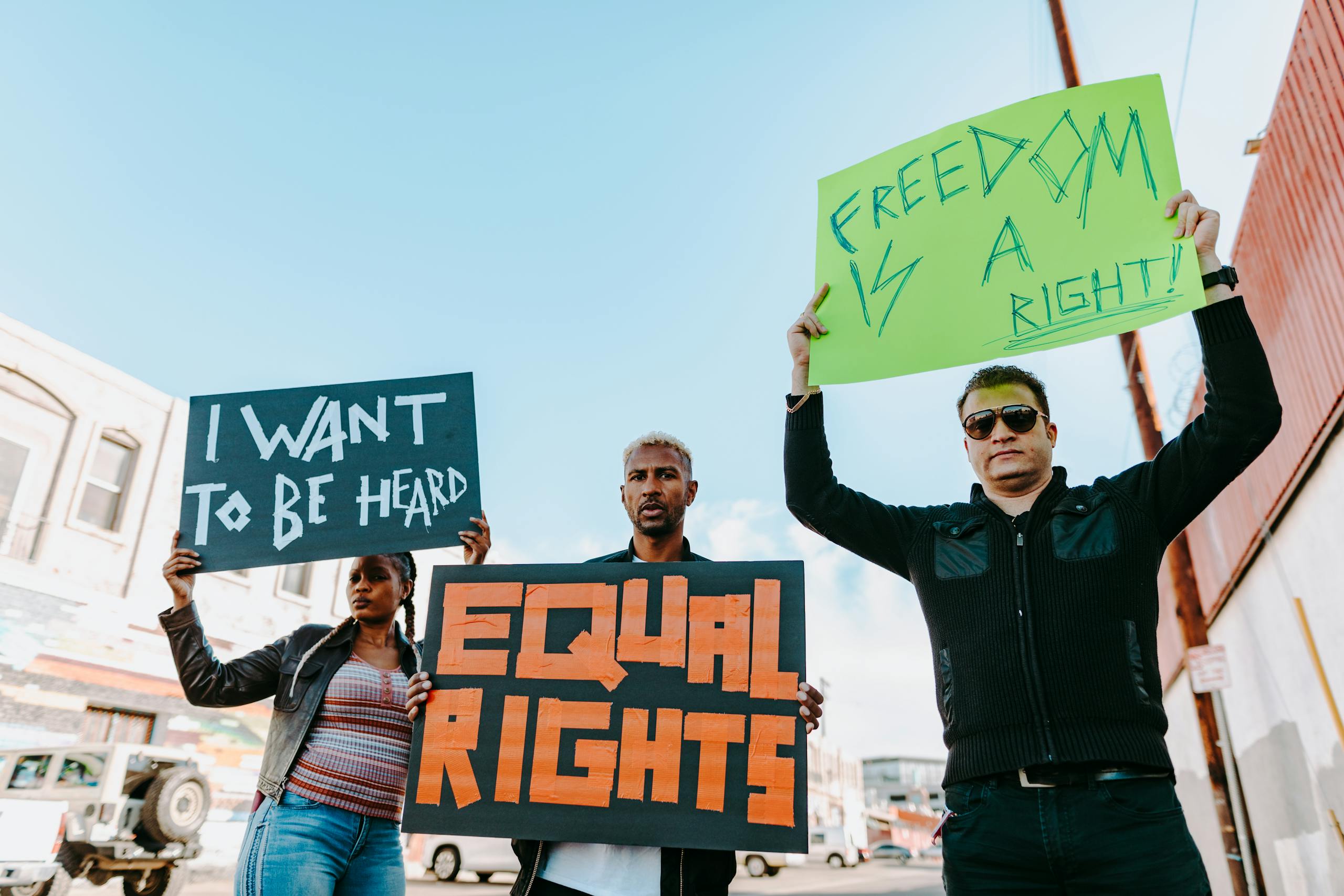 A diverse group of individuals hold protest signs advocating for equality and freedom.