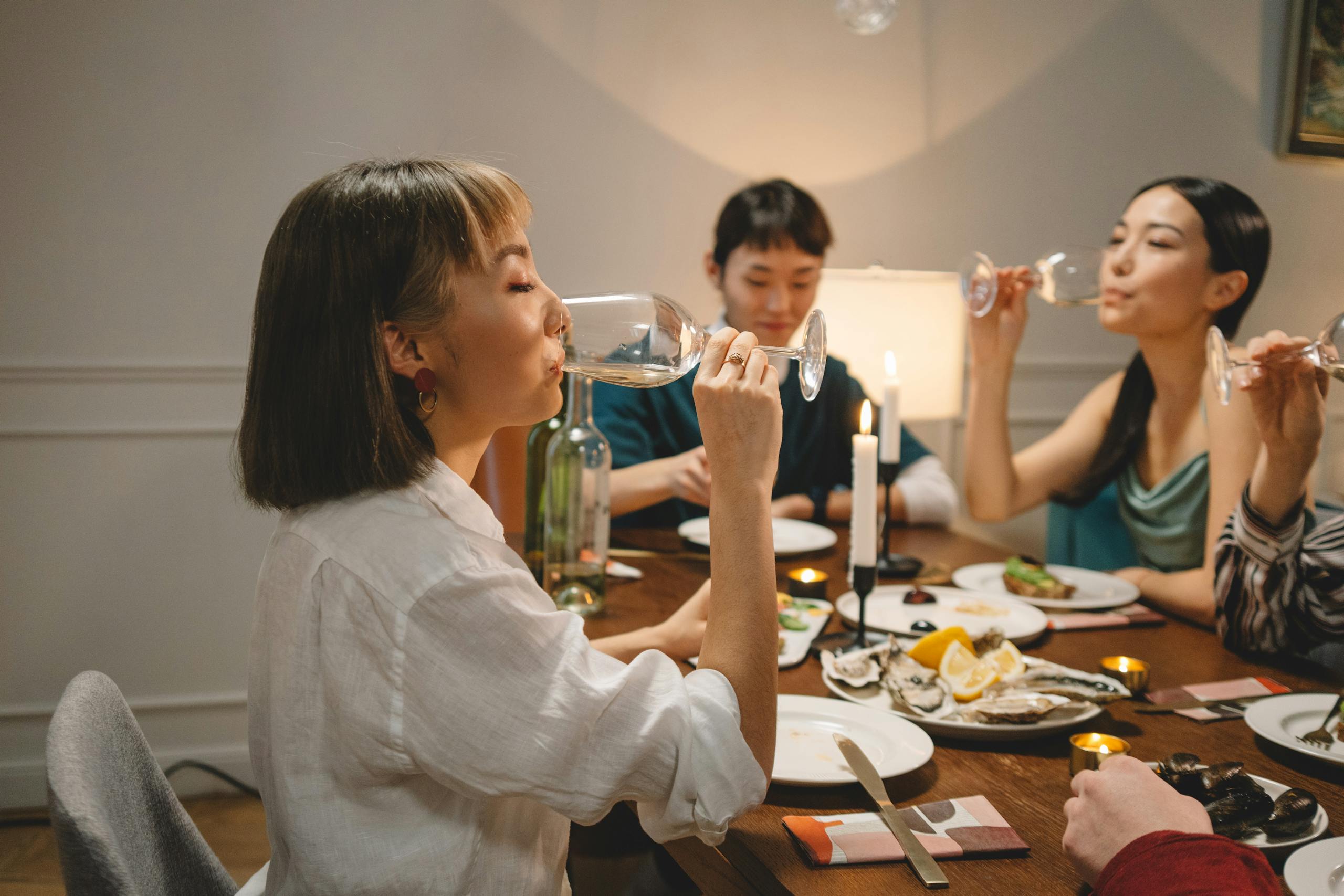 A group of friends gather, enjoying wine and dinner together indoors.