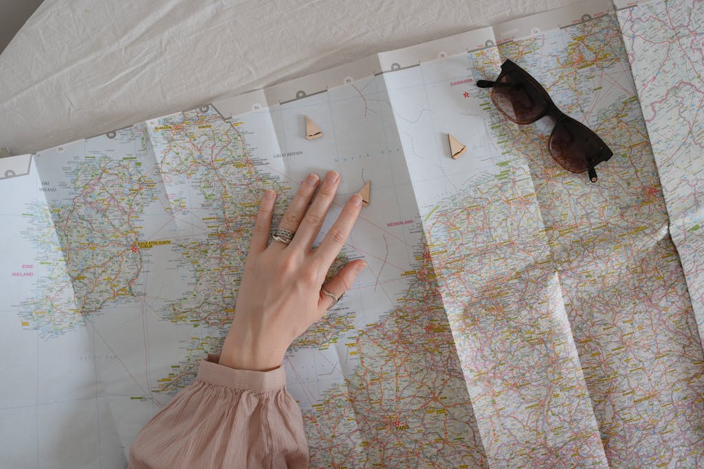 A hand exploring a map with sunglasses for travel planning.