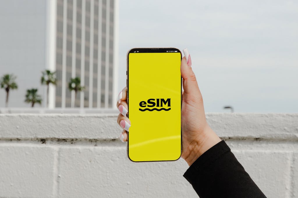 A hand holding a smartphone displaying 'eSIM' against an urban backdrop in Los Angeles.