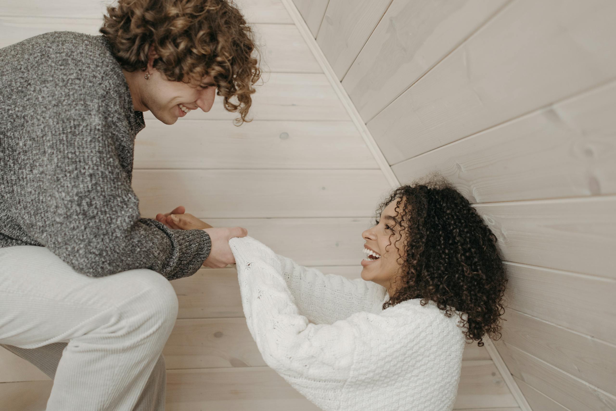 A happy couple shares a joyful and affectionate interaction indoors, embracing each other.