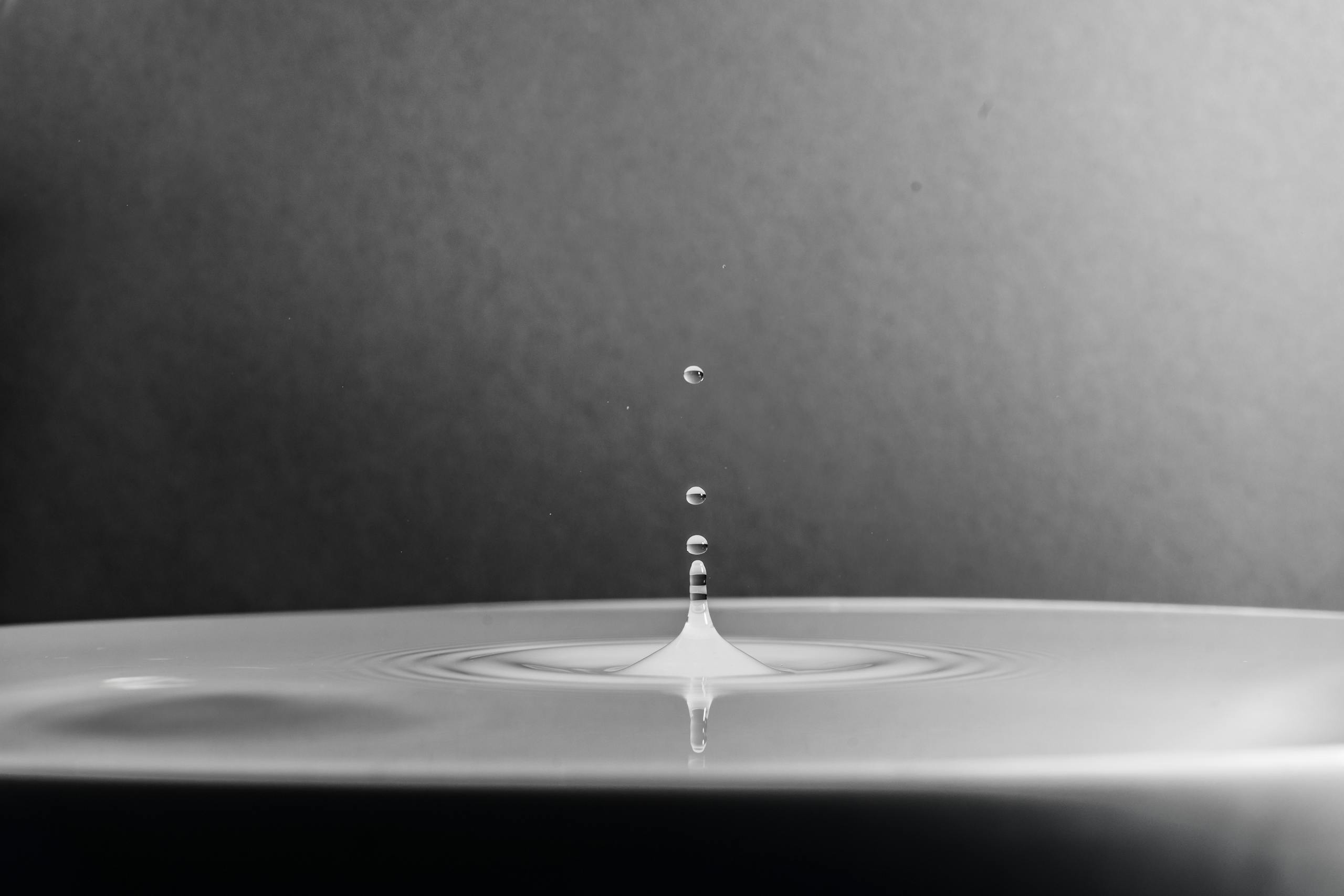 A high-definition macro shot capturing a water drop splash in black and white.