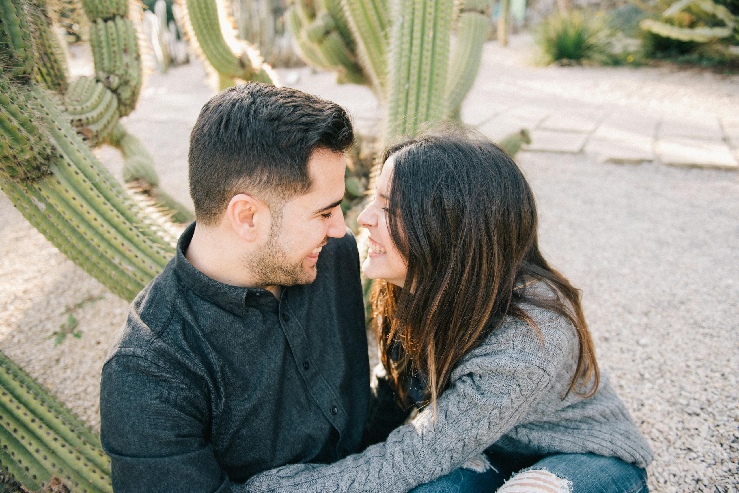 A joyful couple embraces among desert cacti, showcasing love and happiness.