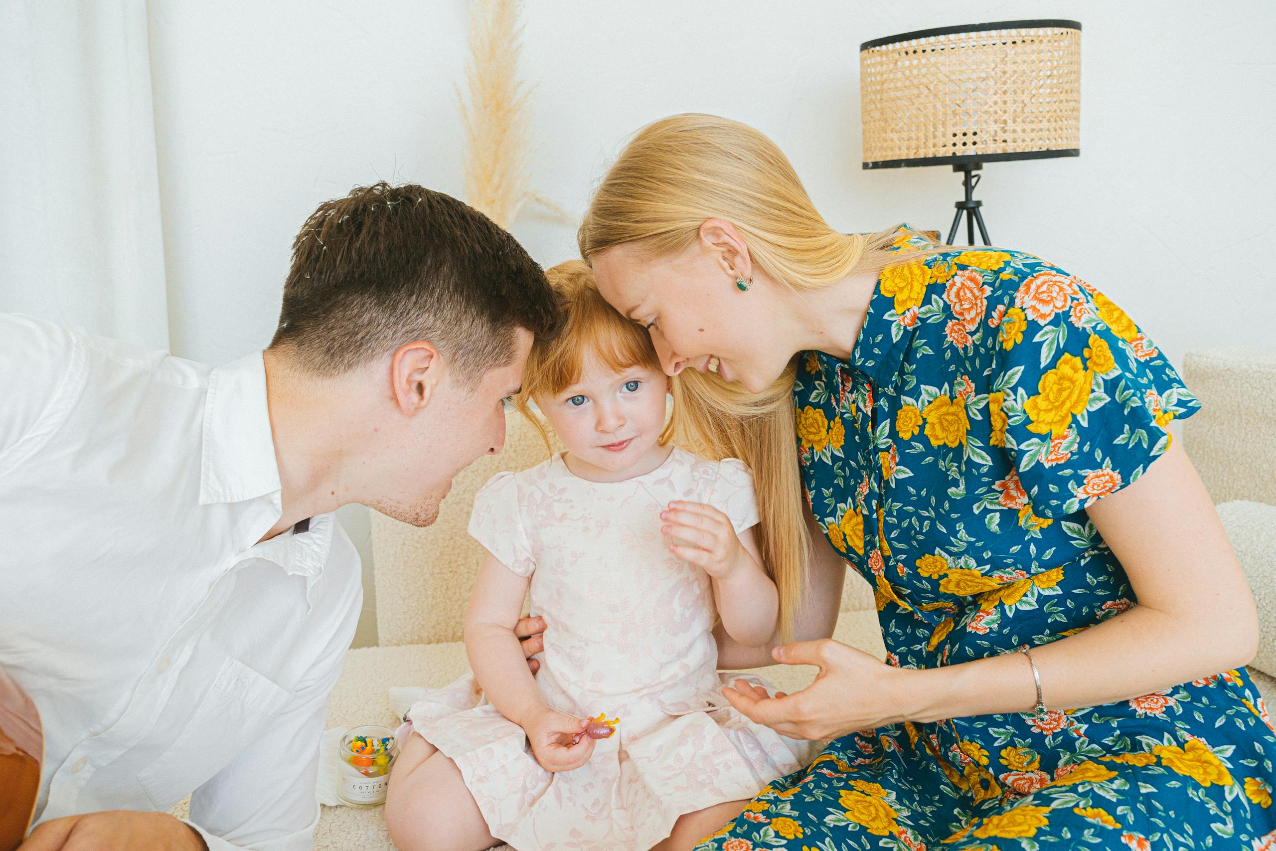 A joyful family moment with parents bonding with their young daughter indoors.
