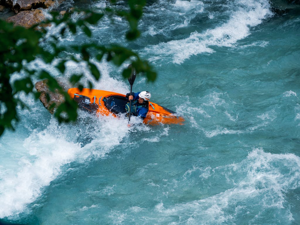 A kayaker skillfully maneuvers through the rapids of the Soča River in Tolmin, Slovenia.