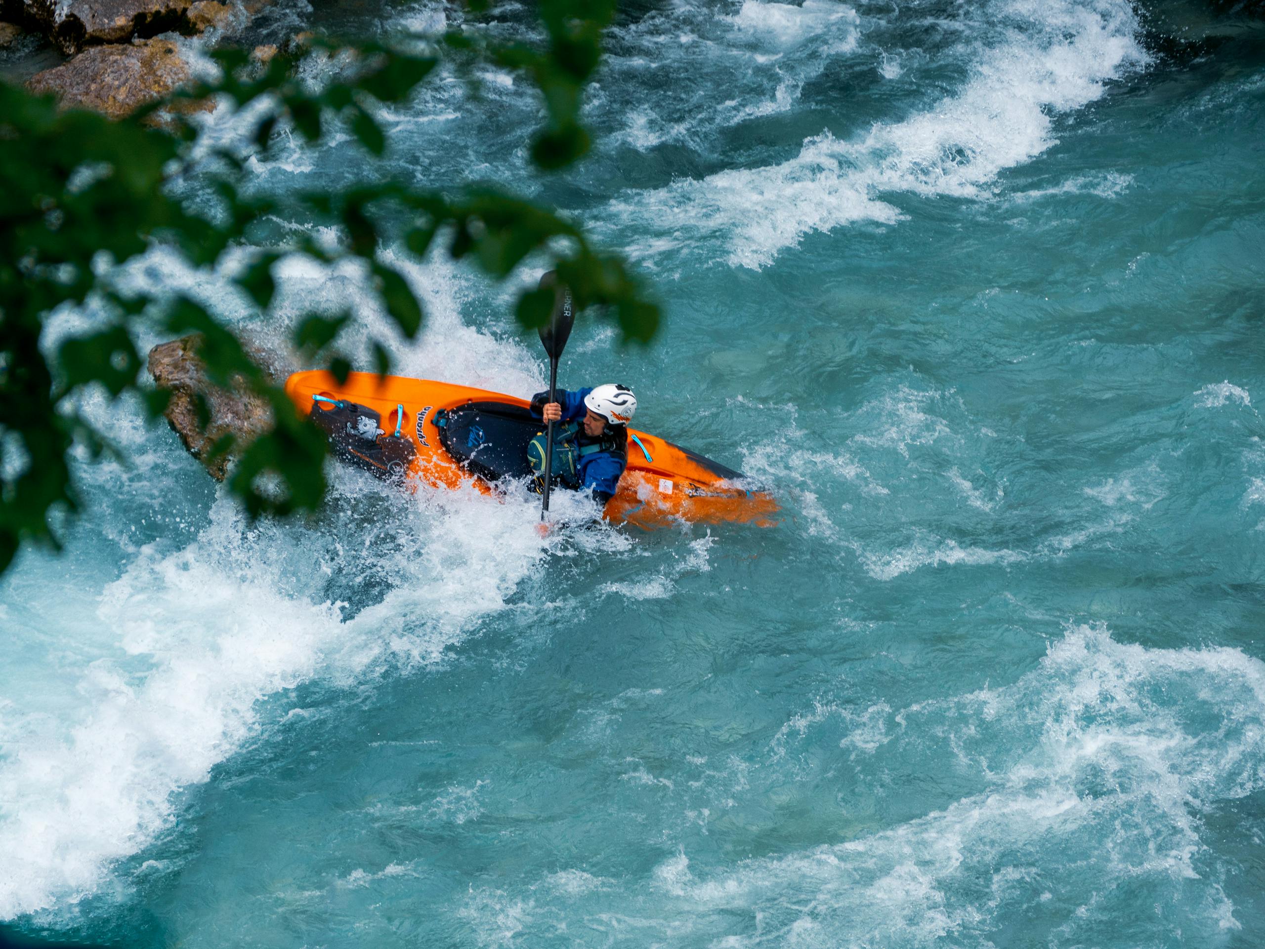 A kayaker skillfully maneuvers through the rapids of the Soča River in Tolmin, Slovenia.