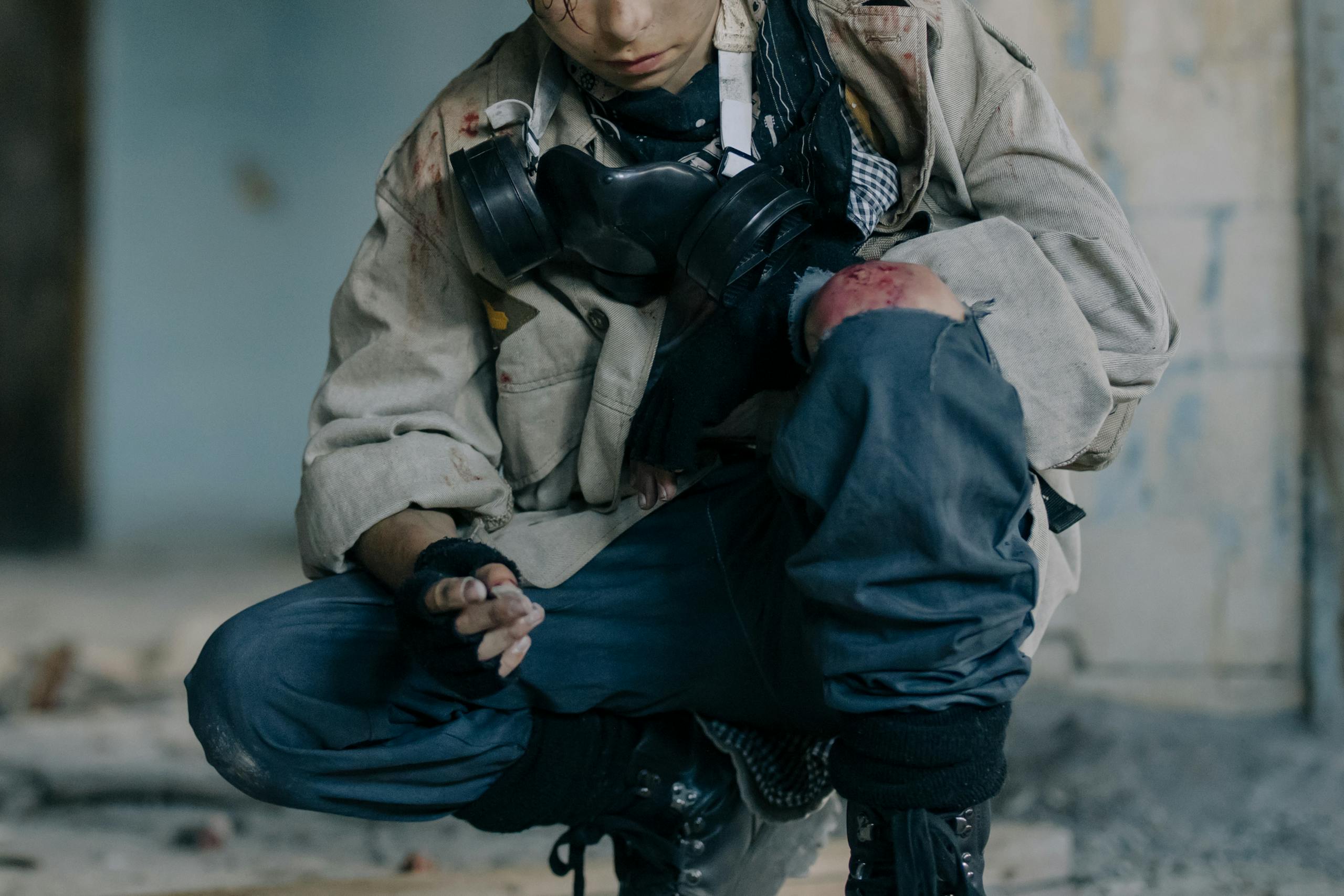 A lone man in rugged attire within a decaying building, embodying survival.
