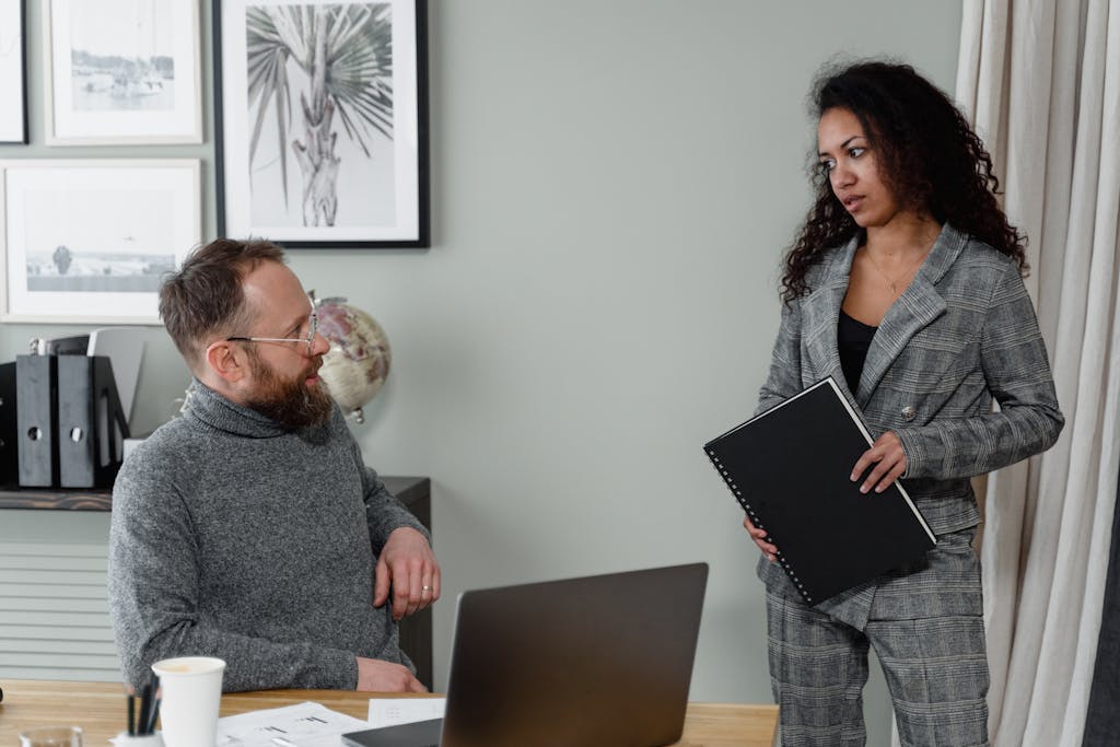 A man and woman discuss work in a stylish office environment with modern decor.