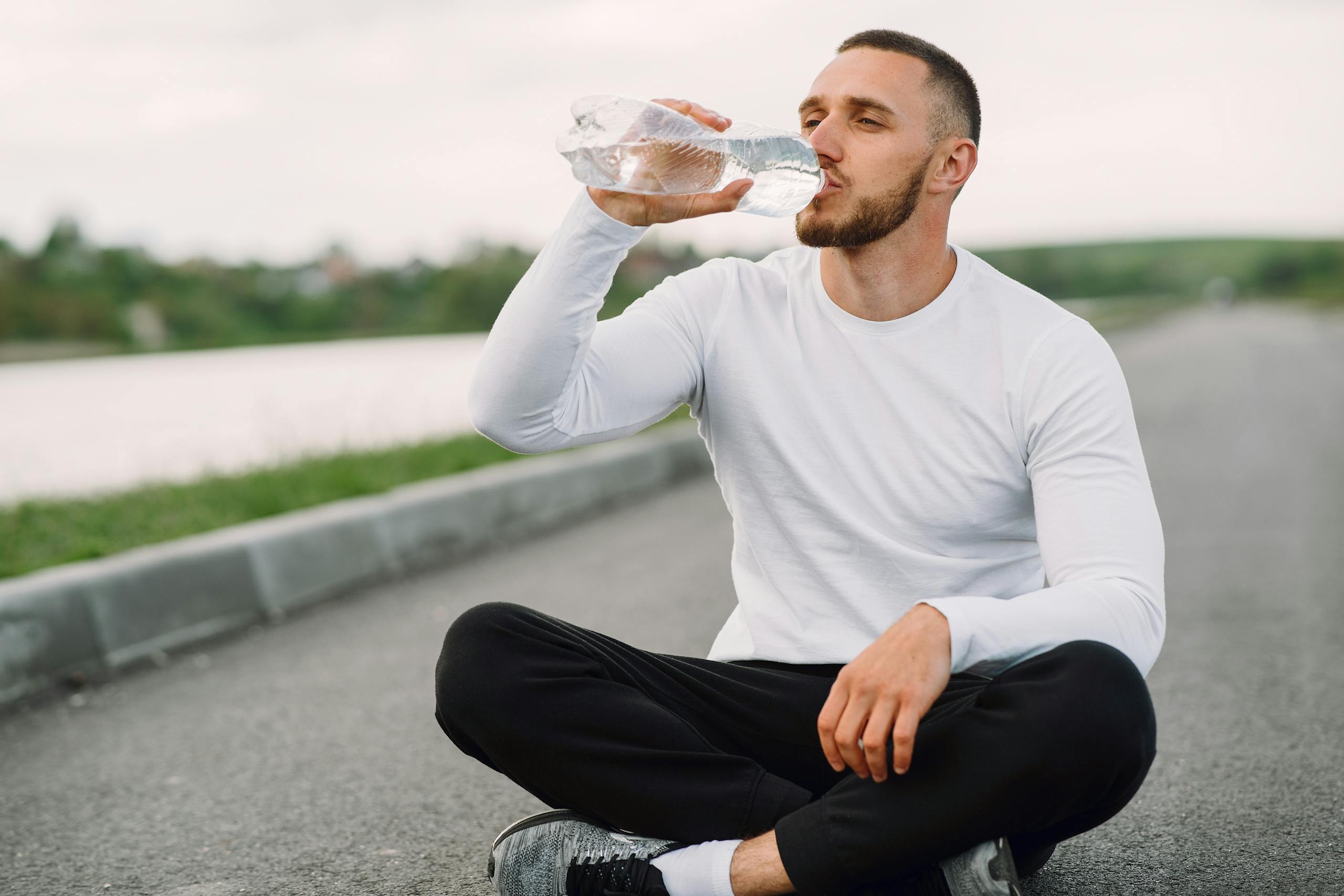A man in sportswear hydrates outdoors, promoting healthy lifestyle and fitness.