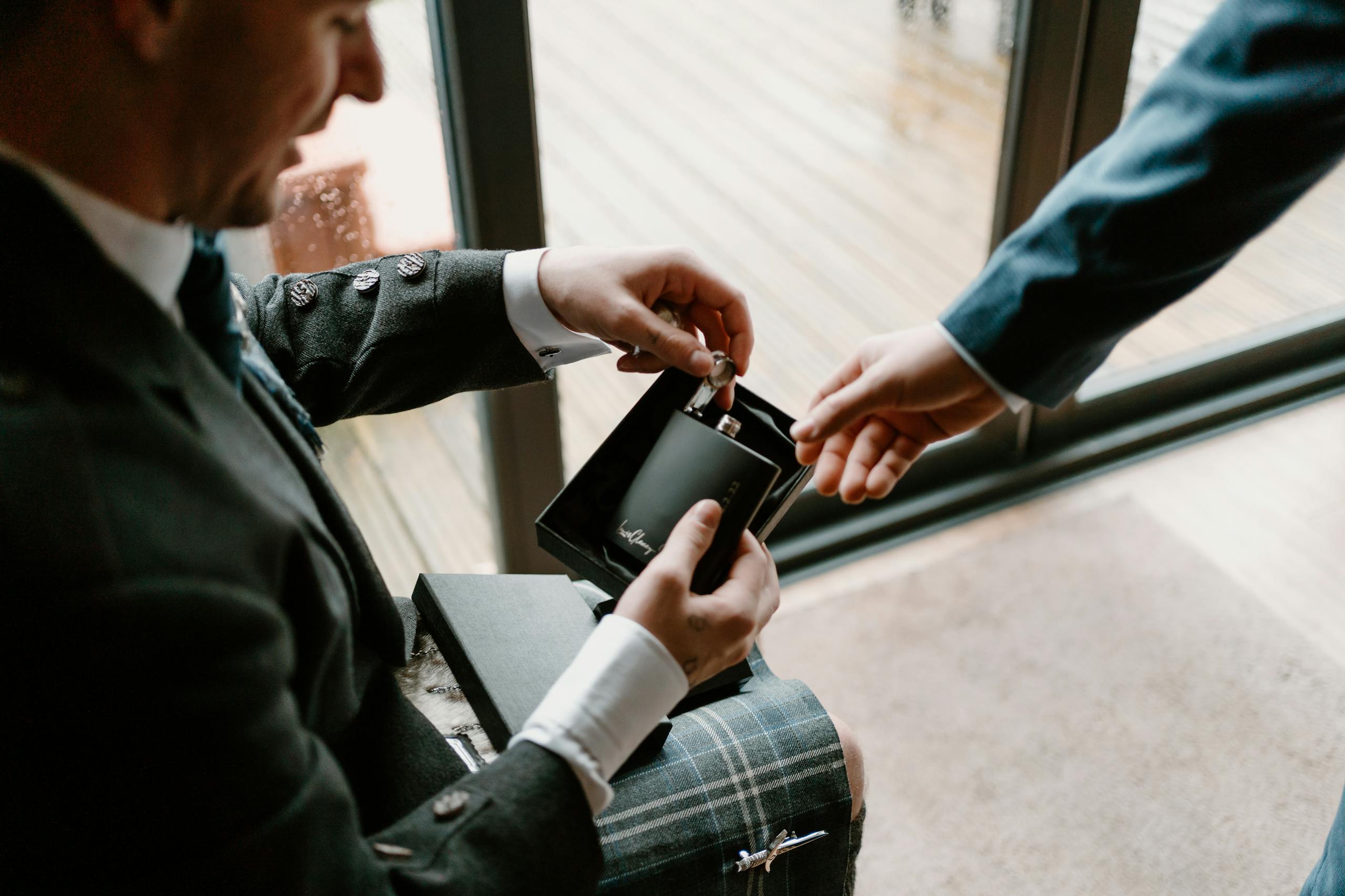 A man presents a perfume gift in a sophisticated setting, highlighting elegance and style.