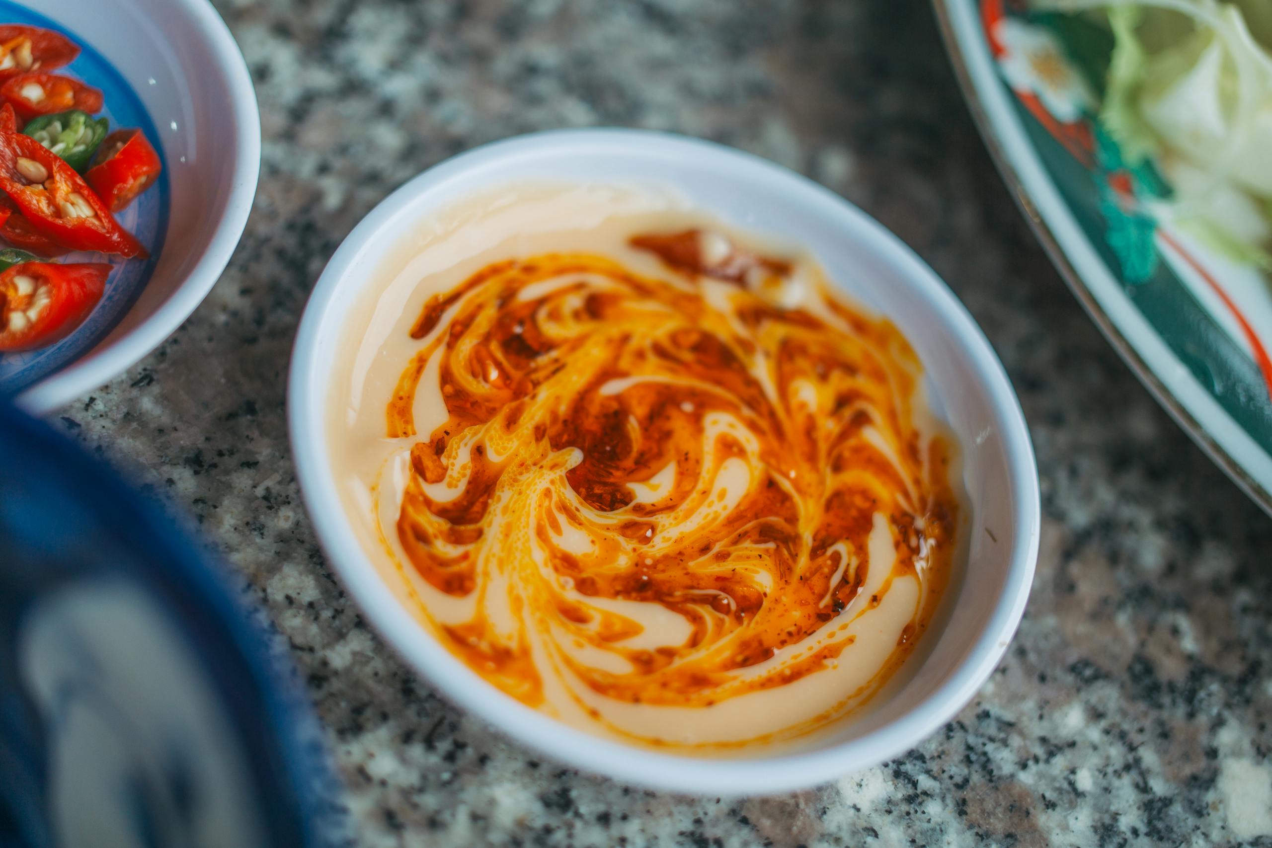 A marble swirl of creamy and spicy sauce in a white ramekin, perfect for dipping.