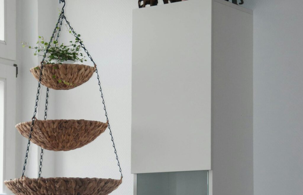 A modern interior with hanging woven baskets and potted plants on a white cabinet, perfect for home decor inspiration.