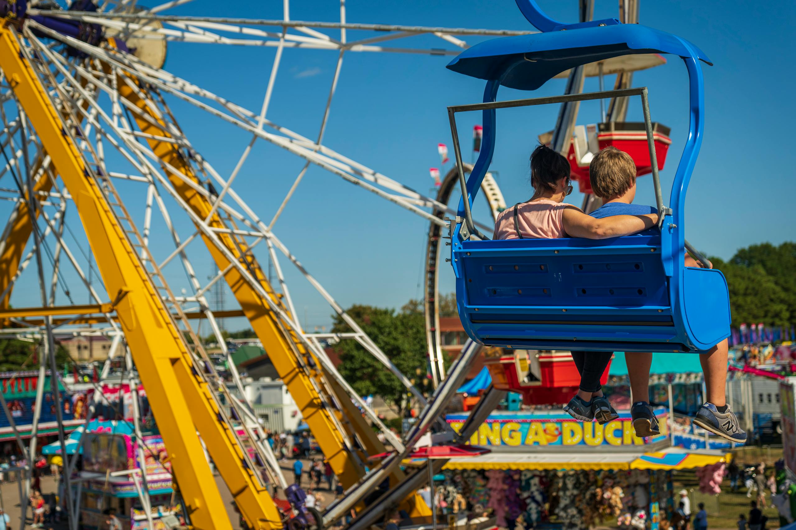 A mother and son share a moment together on a ferris wheel ride at a vibrant carnival.
