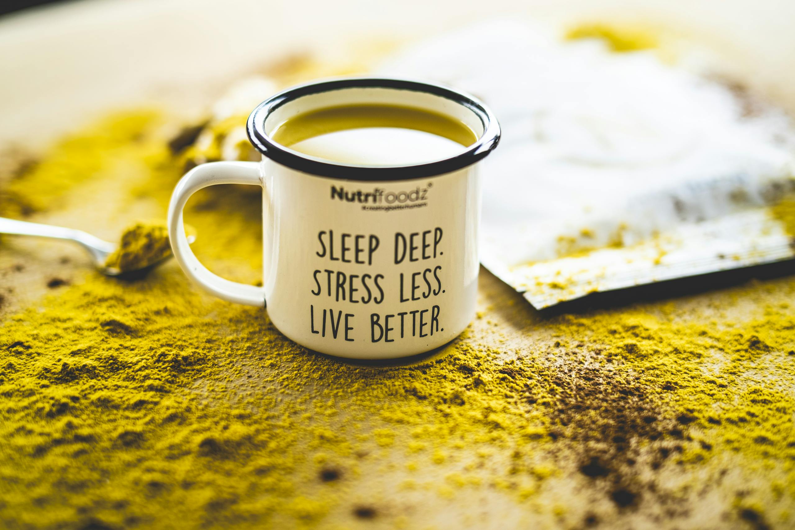 A motivational mug sits on vibrant turmeric powder, promoting relaxation and wellness.