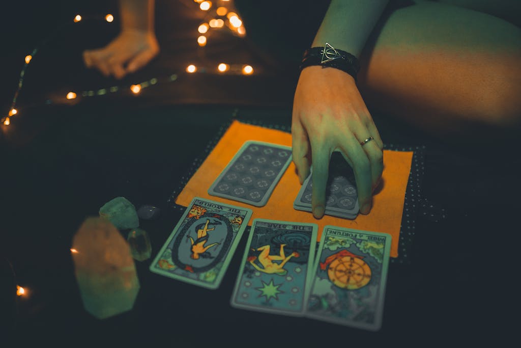 A mysterious tarot card reading featuring a woman's hand under warm ambient lighting.