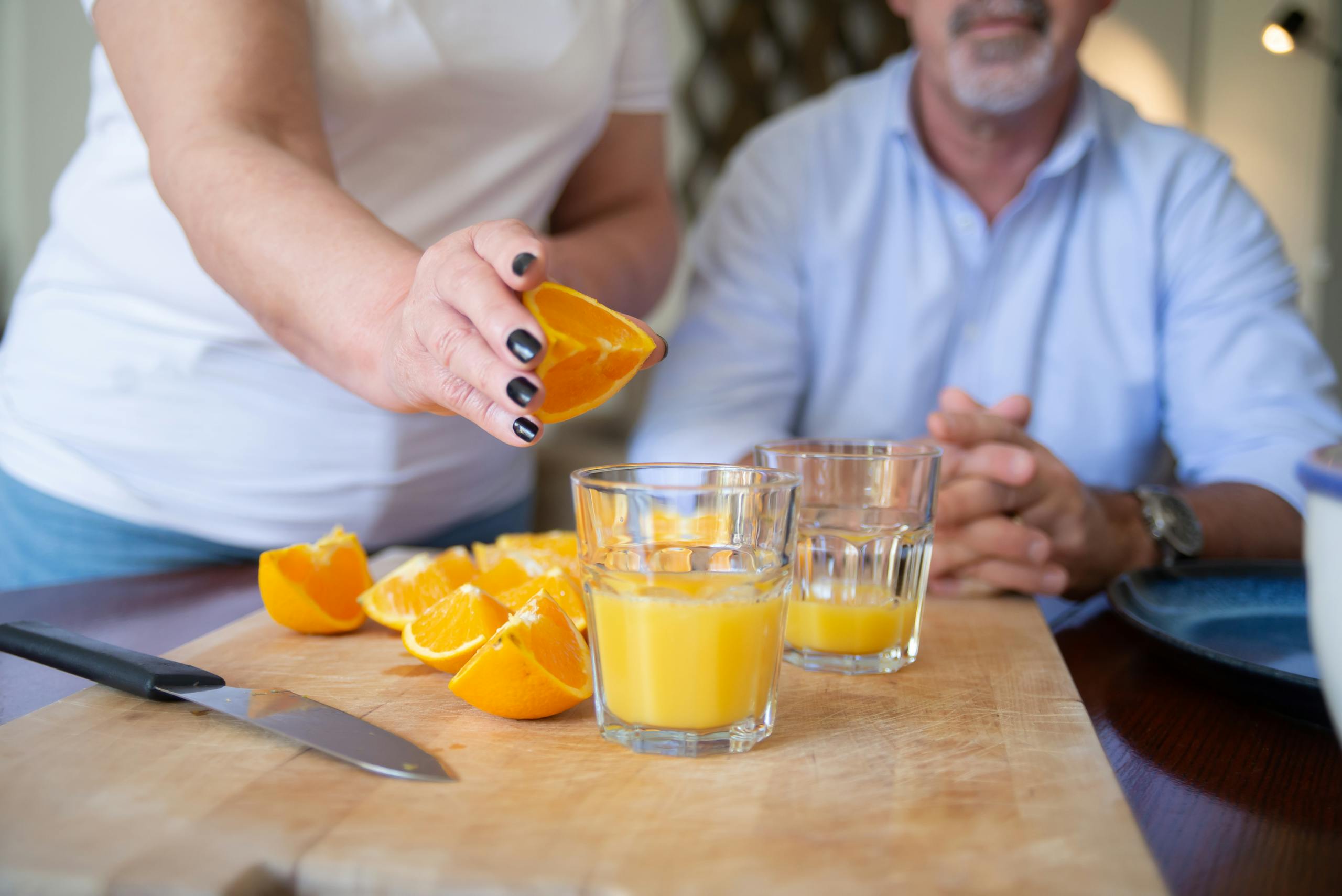 A person preparing fresh orange juice on a chopping board indoors, showcasing healthy lifestyle.