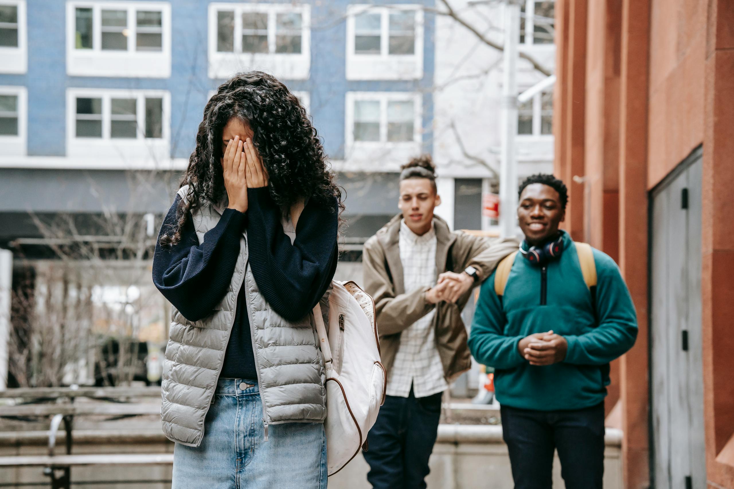 A scene depicting teenage conflict outdoors in an urban area with diverse individuals.