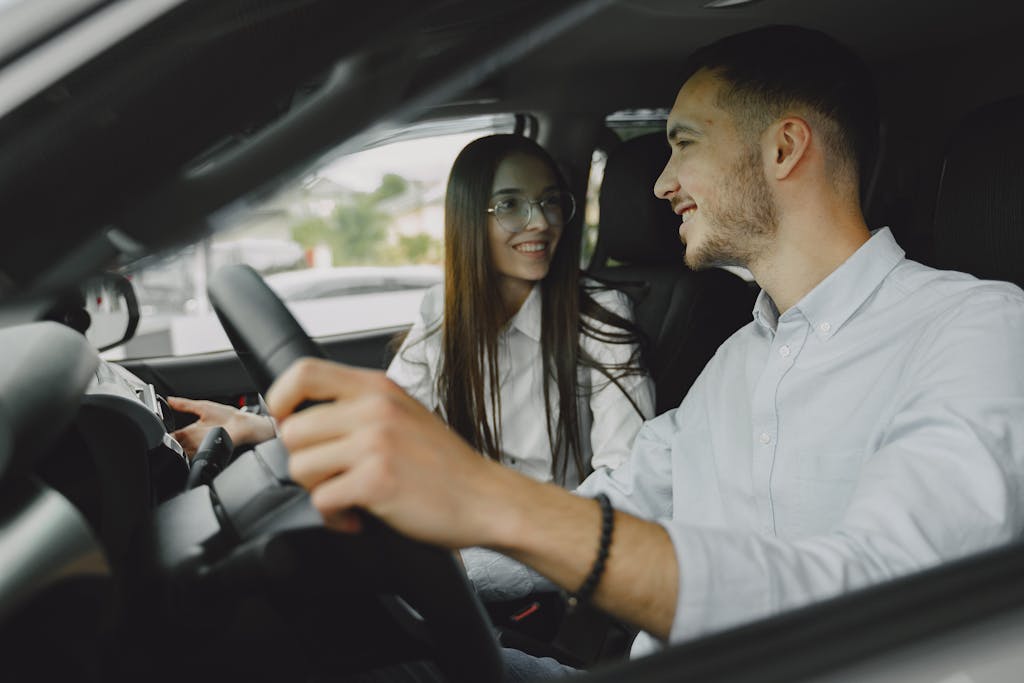 A smiling couple driving together in a car, enjoying their time on the road.