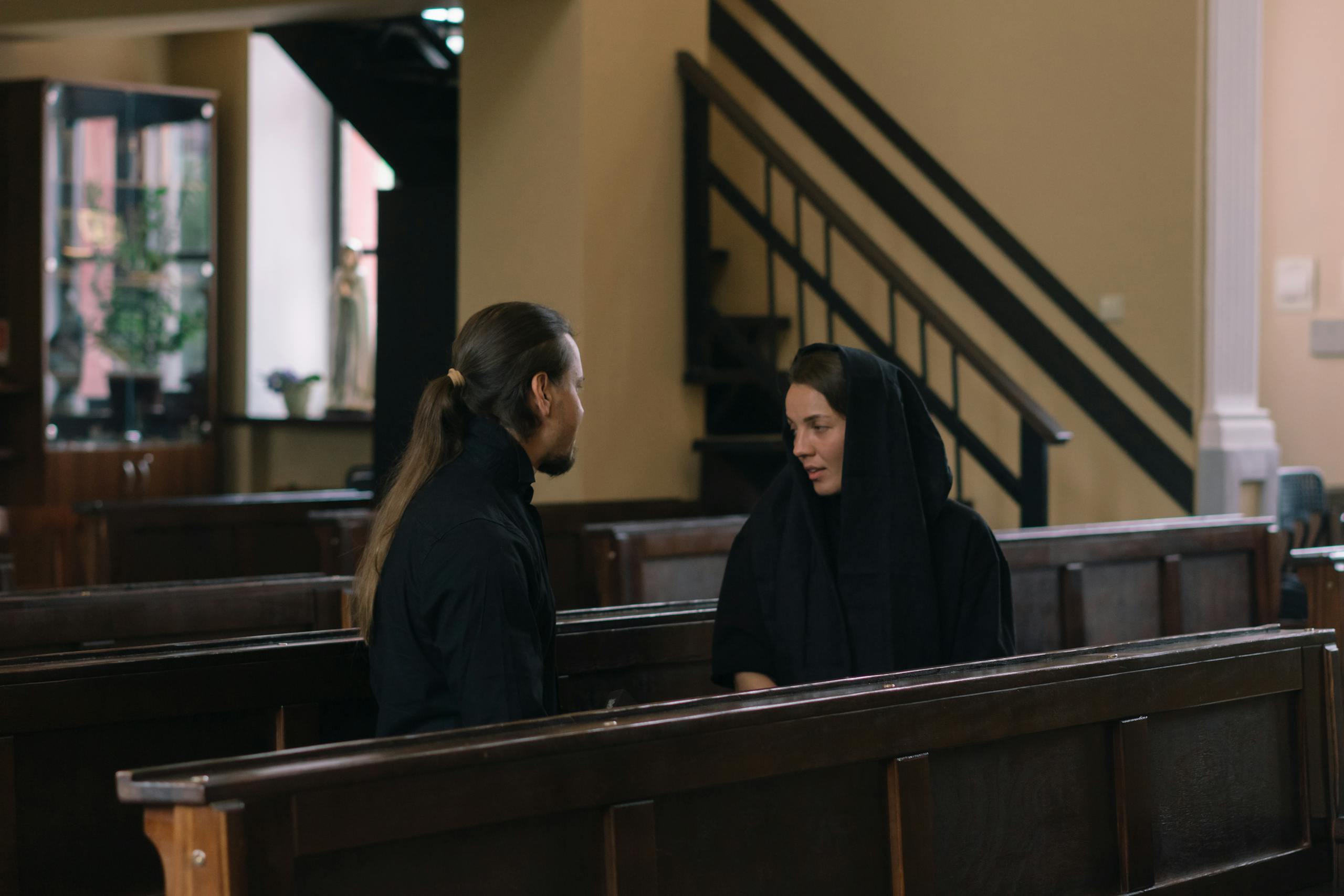 A thoughtful dialogue between a man and a woman in a quiet church setting.