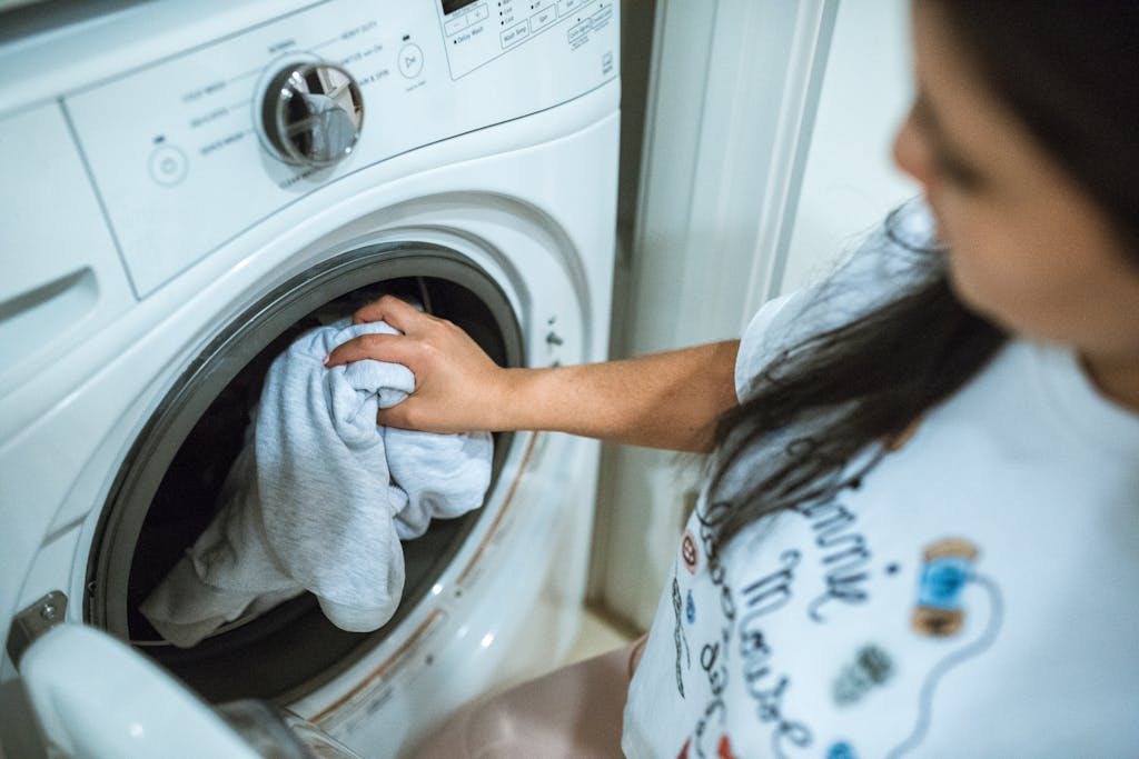 7 Household Appliances Secretly Bleeding You Dry Through Water Waste 4 A woman loading laundry into a washing machine indoors, focusing on household chores.