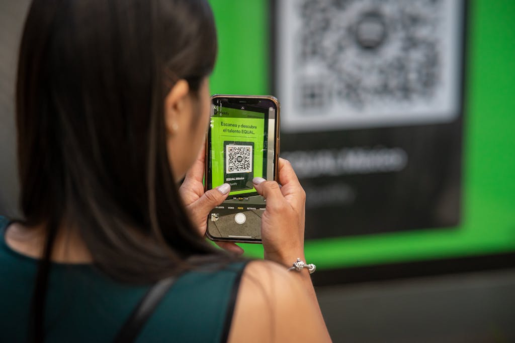 A woman uses her smartphone to scan a QR code in Mexico City, capturing modern technology in action.
