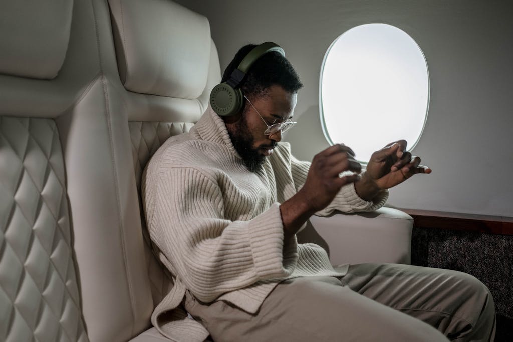 African American man enjoying music with headphones during a flight.