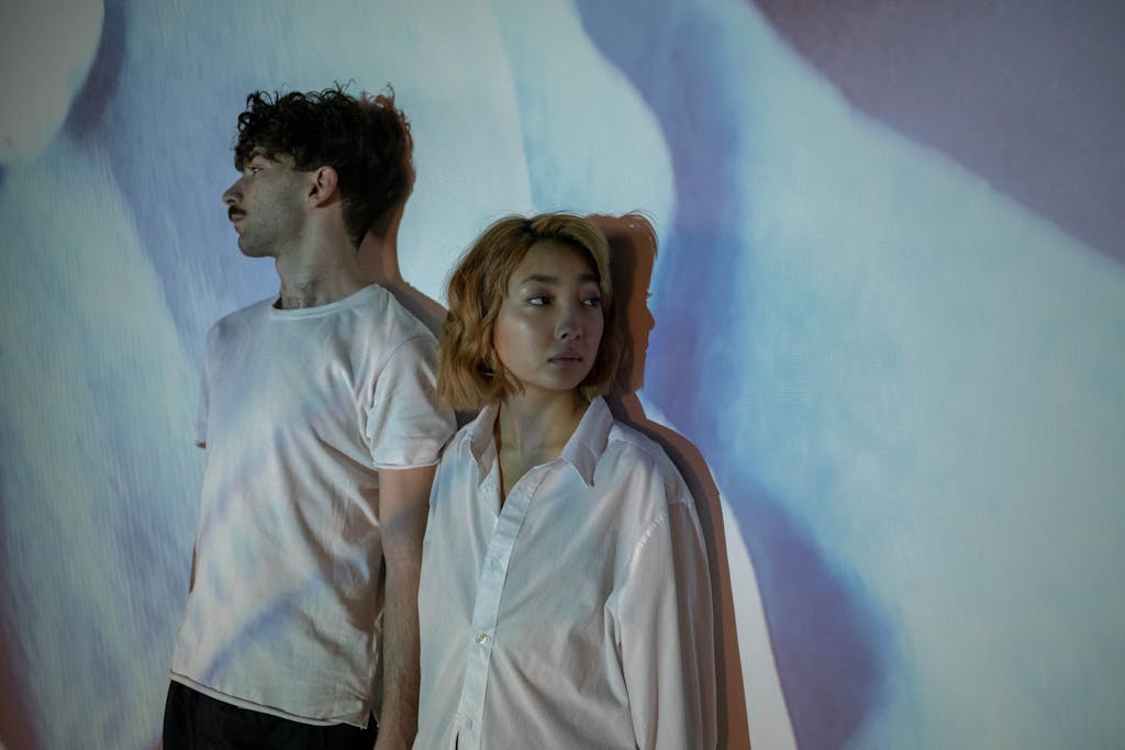 An interracial couple standing apart in an artistic shadow setting, depicting tension and emotional distance.