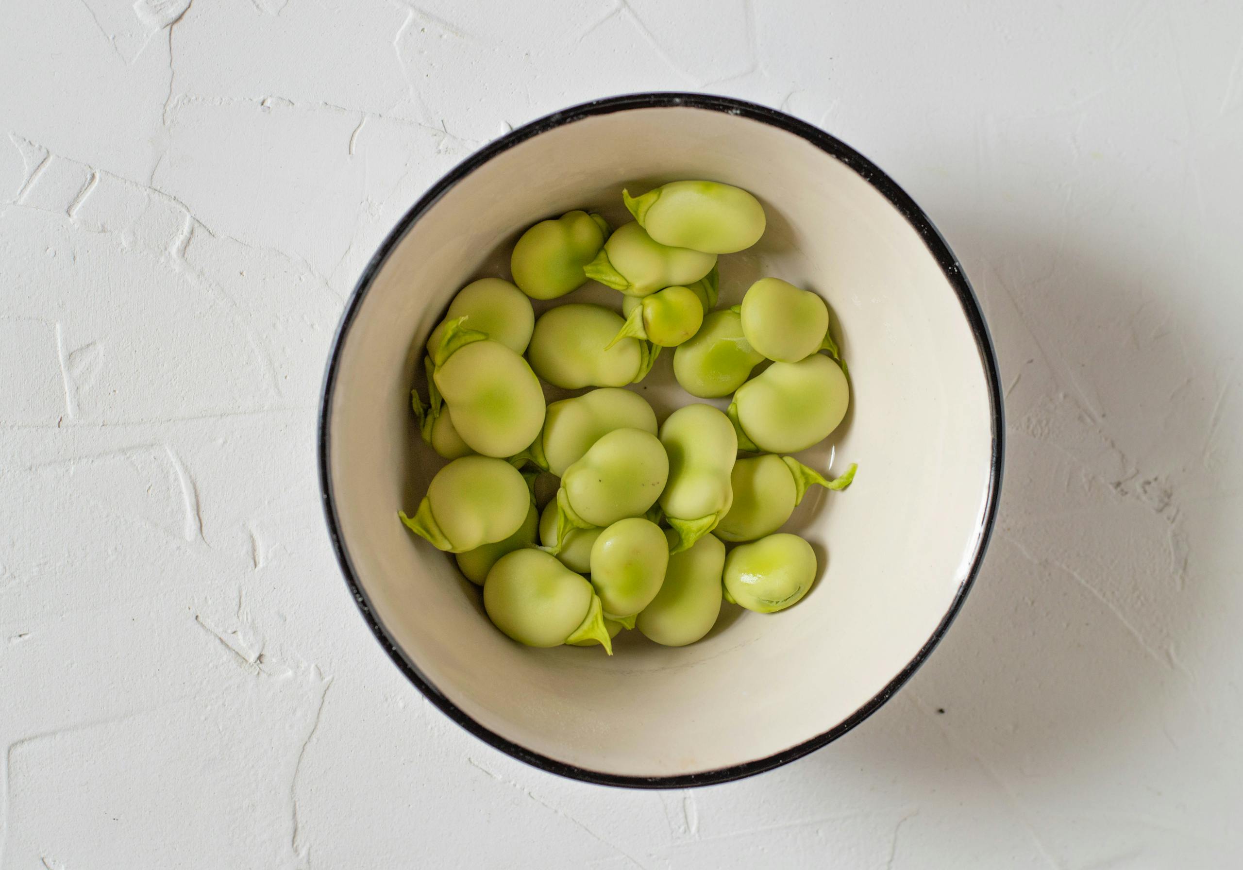 Appetizing broad beans in a white bowl, perfect for healthy food themes.