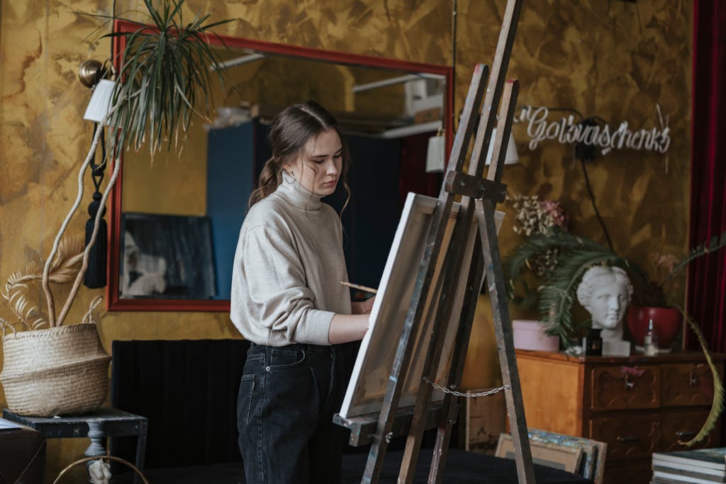 Artist painting on canvas in a stylish studio filled with decor and art objects.
