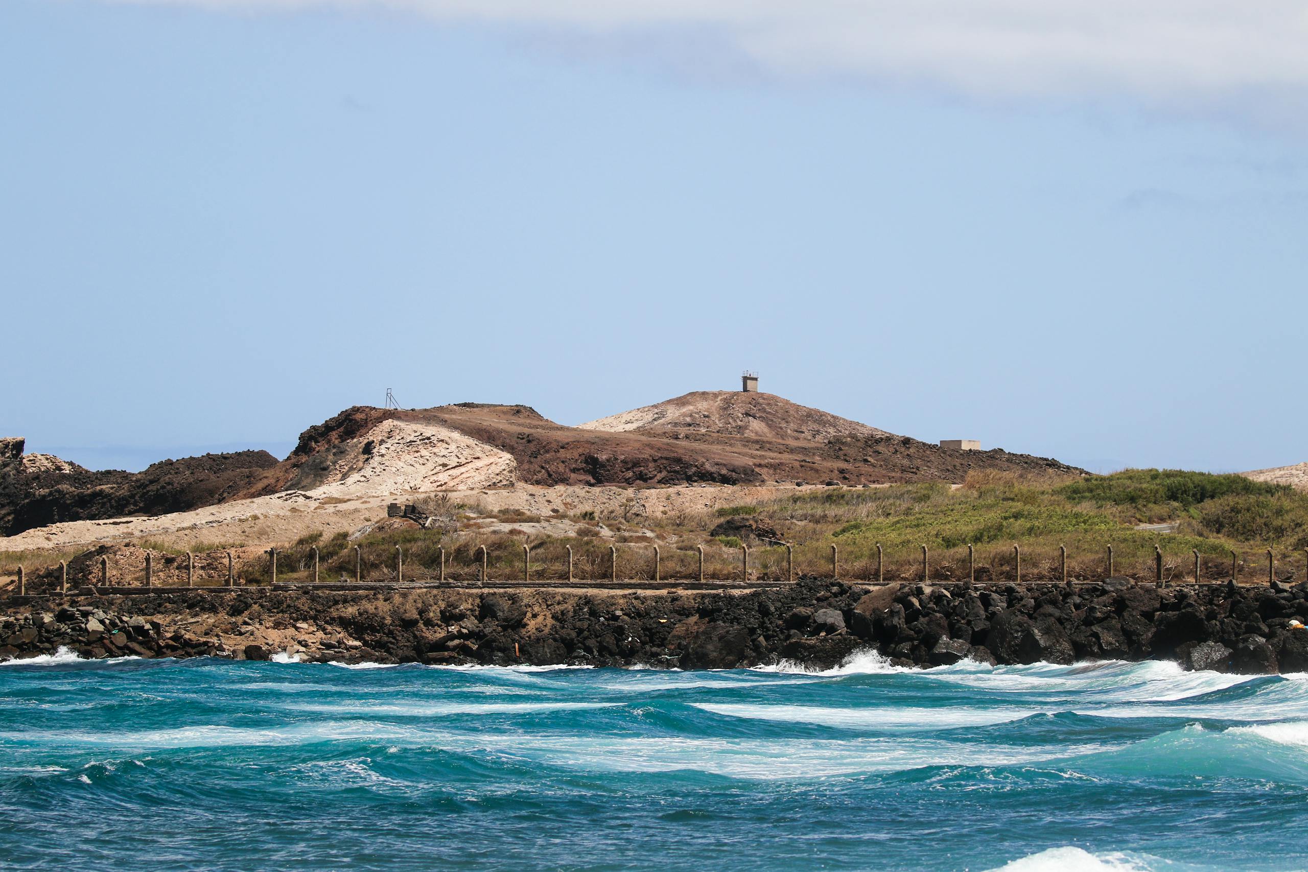 Breathtaking view of Fuerteventura's coastline with waves crashing against rocks under a clear sky.