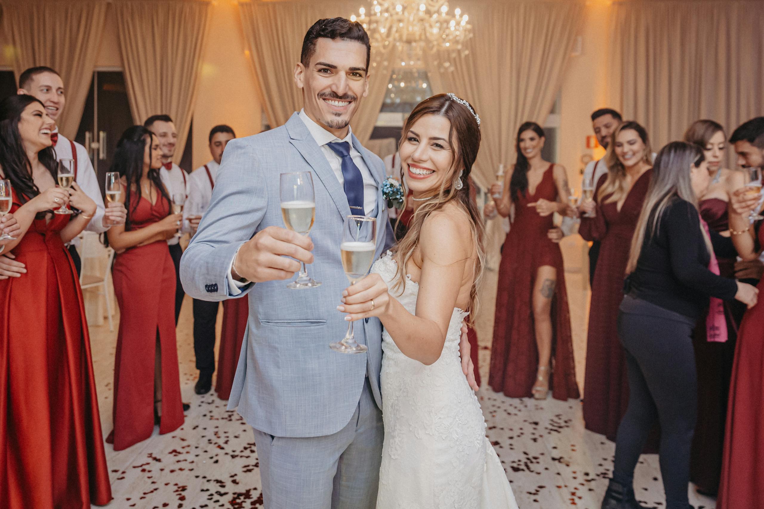 Bride and groom cheerfully toast champagne at their wedding ceremony among happy guests.