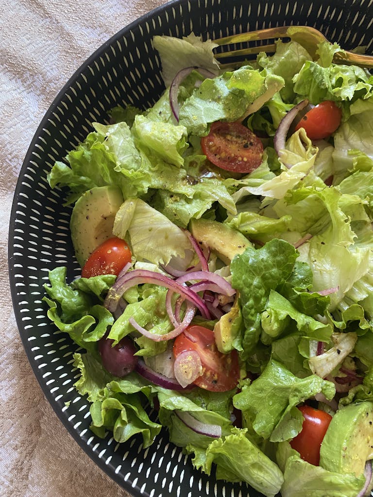 Bright and healthy salad featuring lettuce, avocado, cherry tomatoes, and onions.
