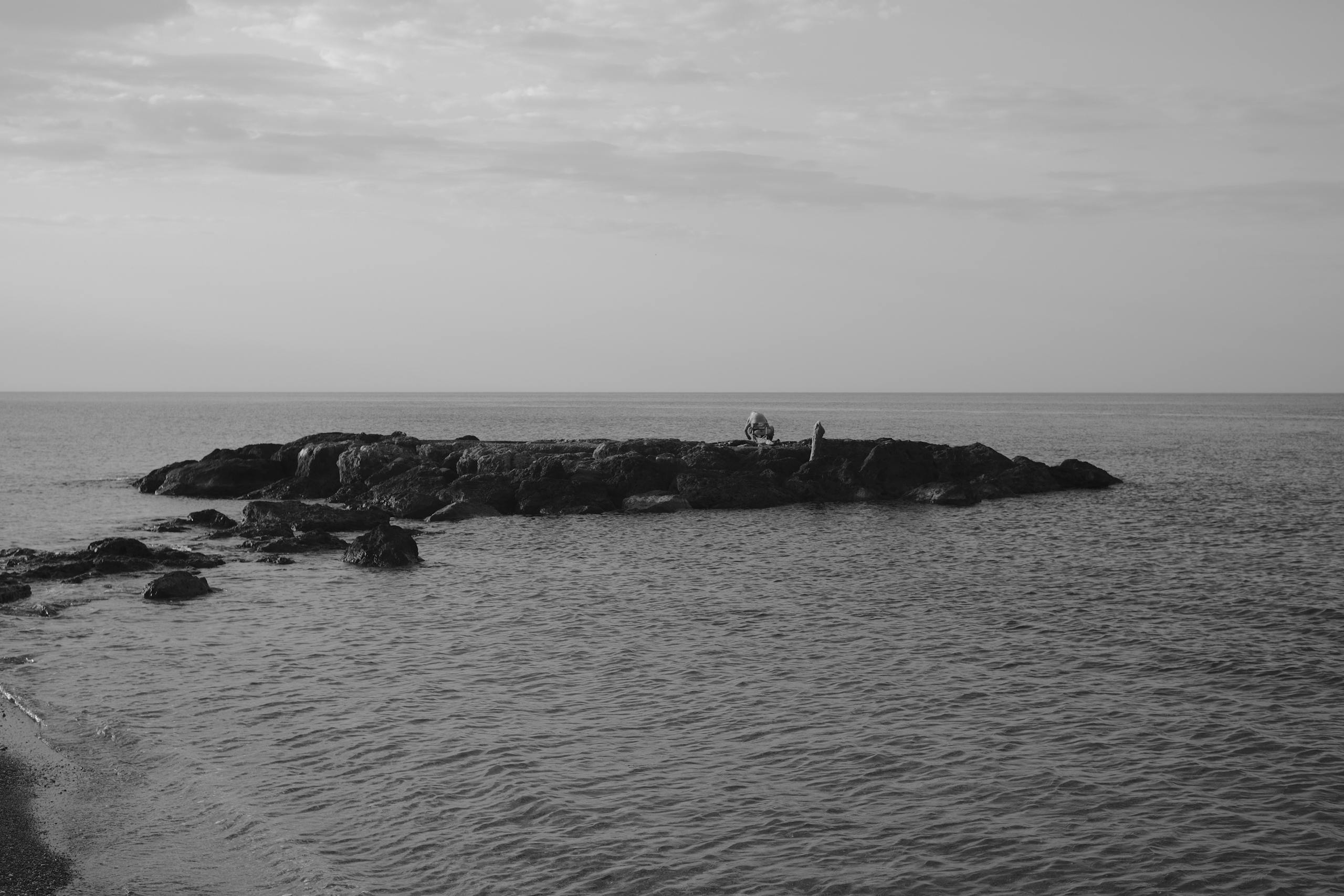 Captivating black and white seascape of a rocky outcrop in Italy, evoking tranquility.