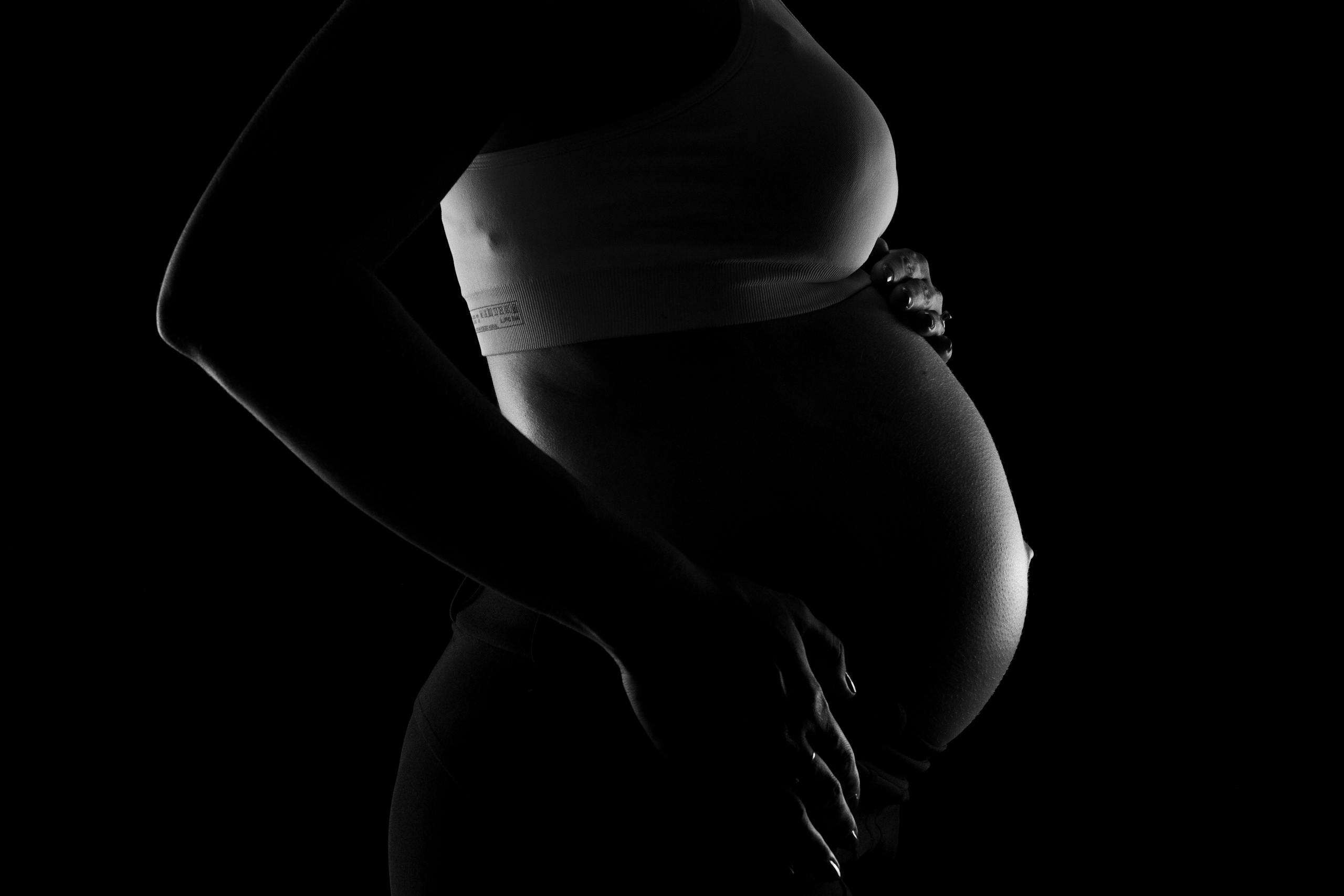 Captivating grayscale close-up of a pregnant woman highlighting a baby bump, conveying anticipation and love.