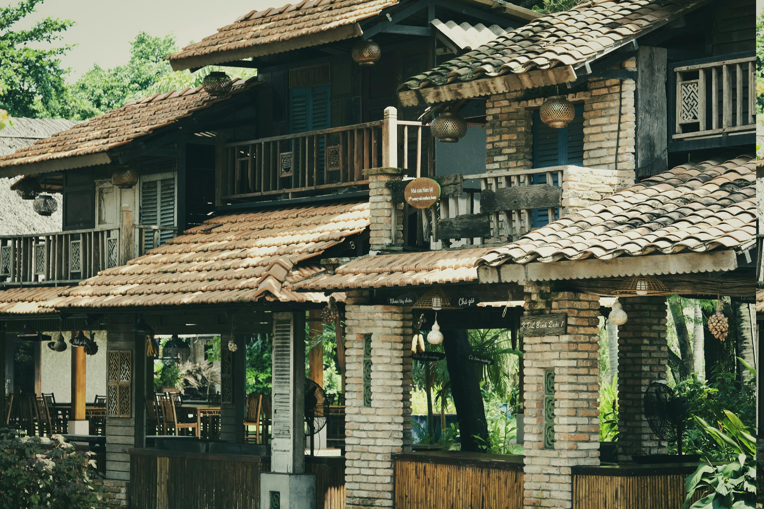 Charming country inn with rustic brick and wood architecture surrounded by lush greenery on a sunny day.