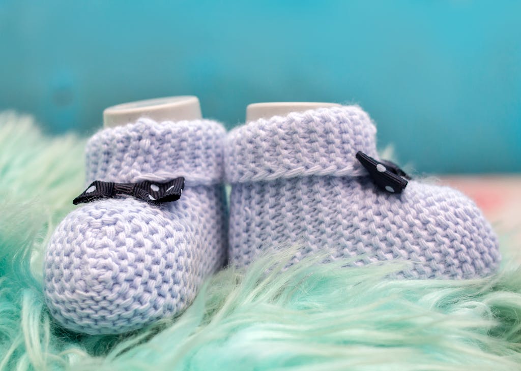 Charming knitted baby shoes with bows set on a soft, fluffy surface against a blue backdrop.