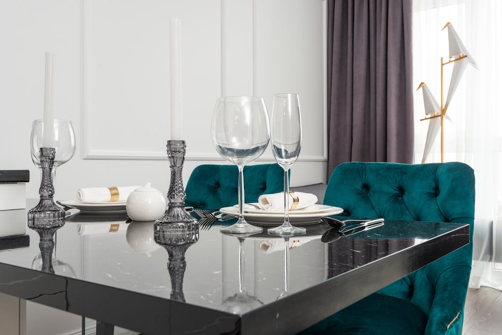 Chic dining room with green chairs, marble table, and elegant tableware setup.