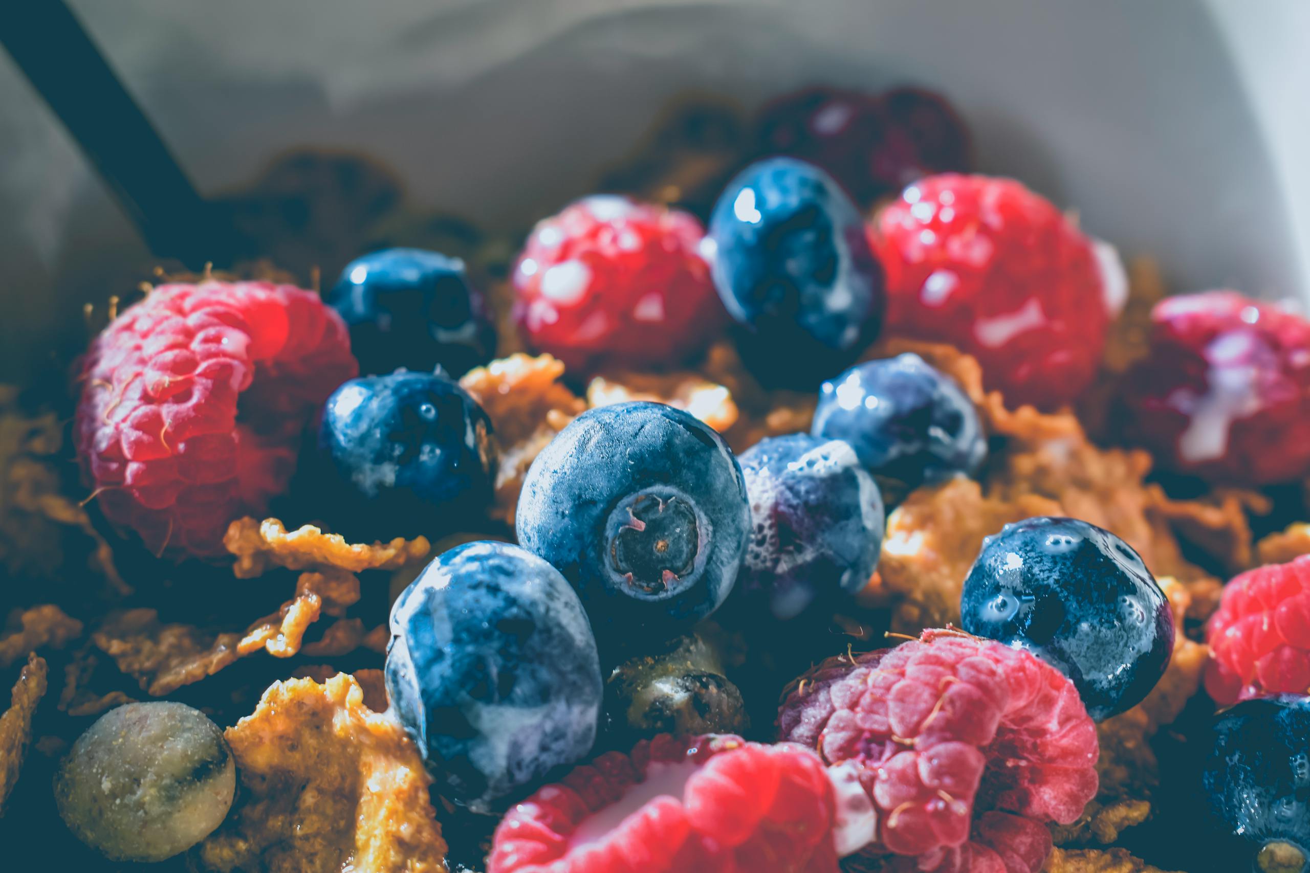 Close-up of a delicious and healthy breakfast with fresh blueberries and raspberries on cereals.