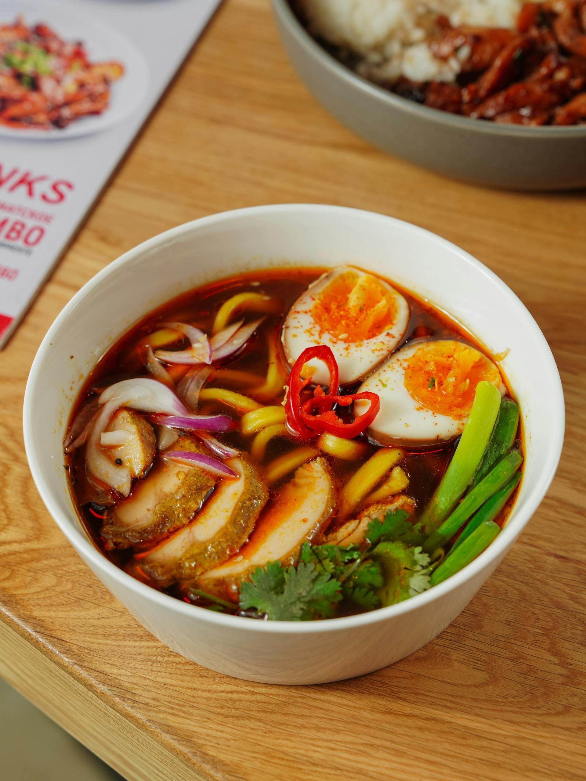 Close-up of a flavorful Asian ramen bowl topped with boiled eggs, vegetables, and chili.