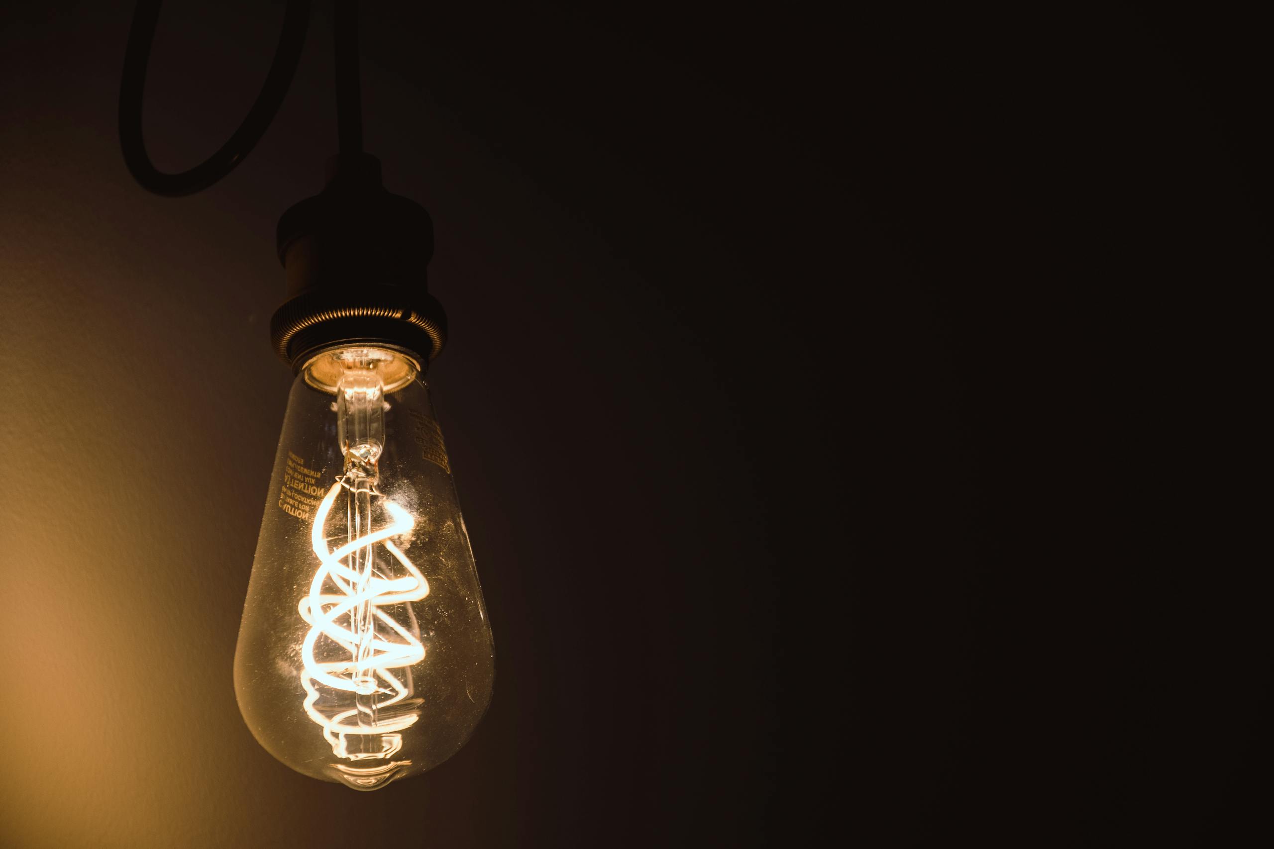 Close-up of a glowing Edison light bulb showcasing its intricate filament.
