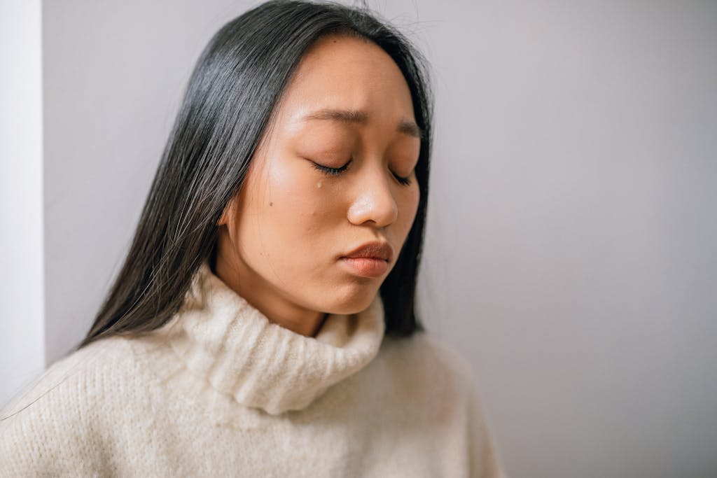 Close-up of an Asian woman with tears, showcasing emotional depth and sadness.