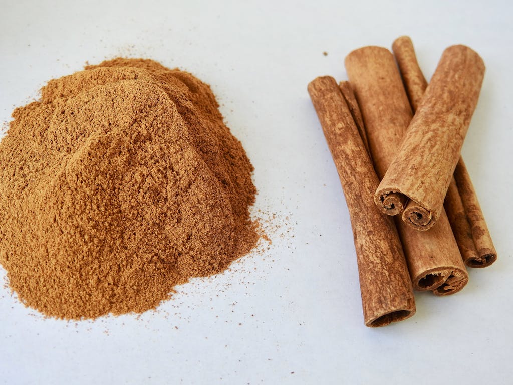 Close-up of aromatic cinnamon sticks and cinnamon powder on a white surface.