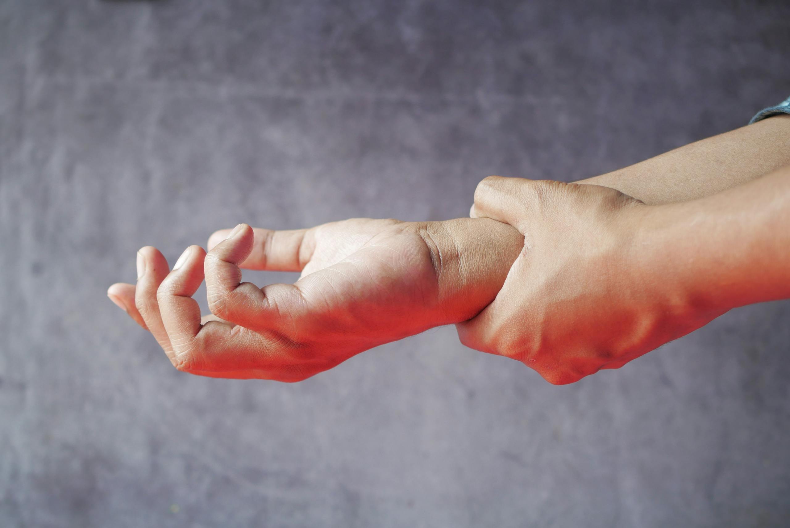 Close-up of hands, one grasping the other, symbolizing pain or discomfort.